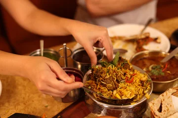 Close Up of Hands Serving Traditional Indian Lamb Biryani at Restaurant © blueringmedia