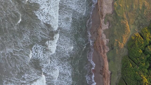 Orilla del mar con olas chocando contra acantilado, naturaleza costera vista cenital a&eacute;rea