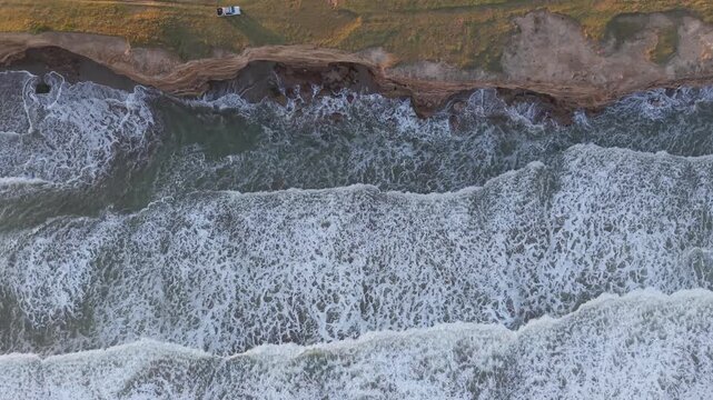 Orilla del mar con olas chocando contra acantilado, naturaleza costera vista cenital a&eacute;rea