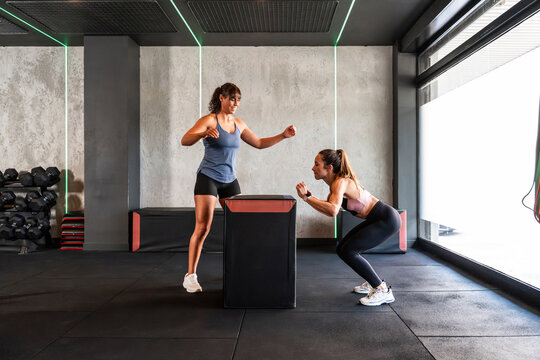 Women training in gym with plyometric box and squat drill