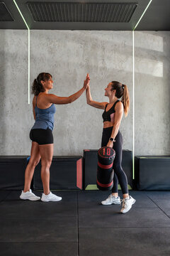 Two women celebrate workout success with a gym high five