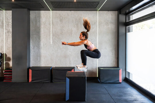 Woman doing box jump plyometric workout in modern gym