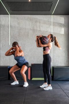 Female coach guiding athlete during sandbag strength lift