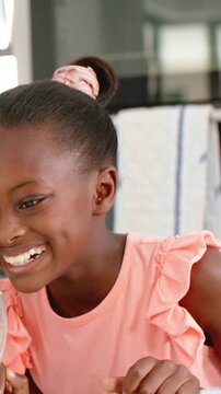 Vertical video: Laughter starting, child in pink top reaching for juice at home table for snack