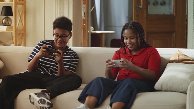 Cheerful African American children competing in an online video game on phones