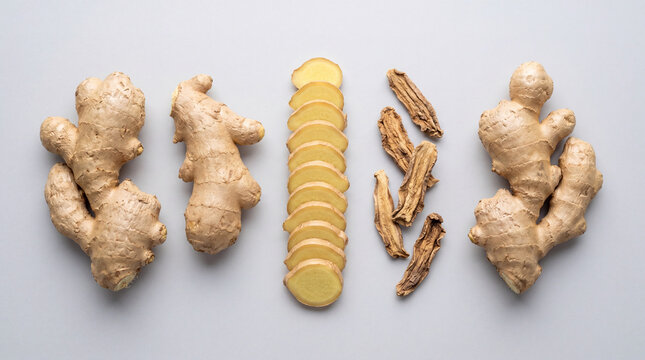 Fresh ginger root and slices arranged on a light surface with dry ginger pieces placed in the middle during a kitchen display