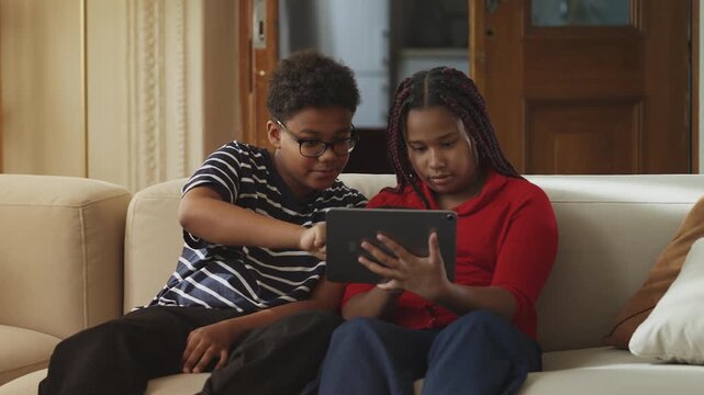 Focused African American children playing educational games on a digital tablet