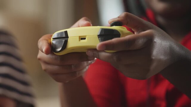 African American child pressing buttons on a gamepad while playing online games
