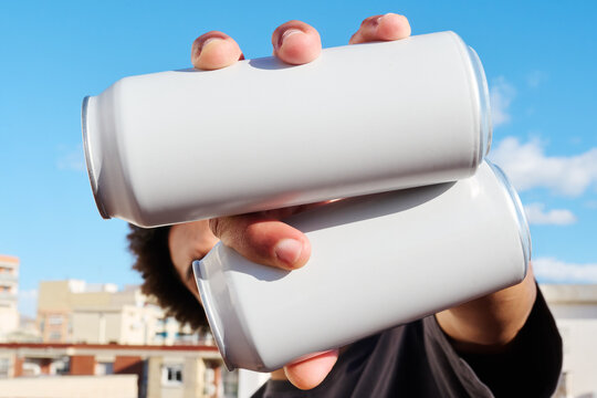 Hand holding two white cans