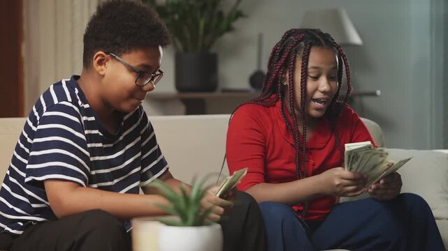 Pleased African American siblings counting dollars and high-fiving, savings