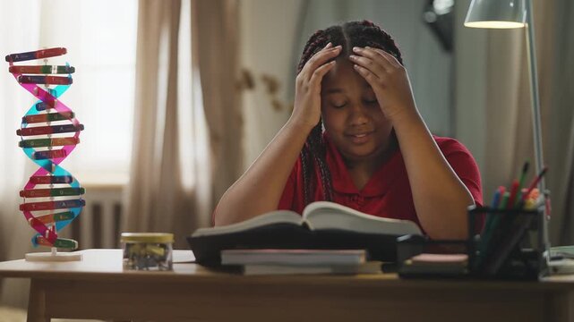 Schoolgirl writing in a notebook while studying in a noisy room at home