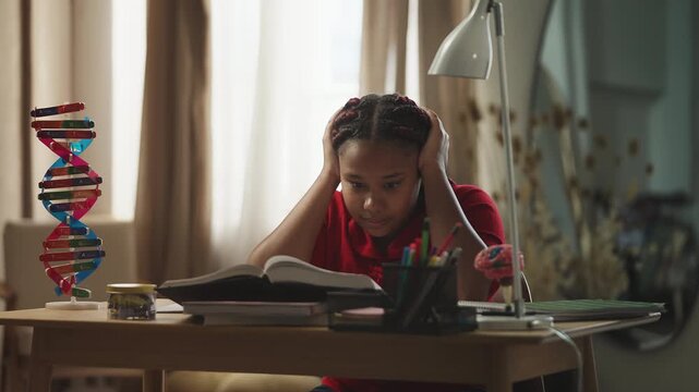 Tired African American girl trying to do homework in a noisy room at home