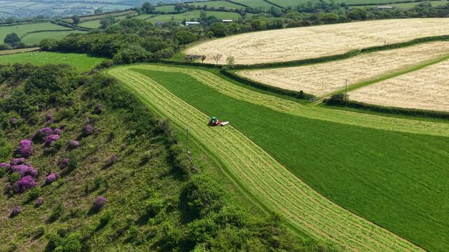 Farming Field Landscape with Tractor mowing green field in English South West Countryside during spring. Agricultural industries, commercial landscaping, rural lifestyle. 4K.