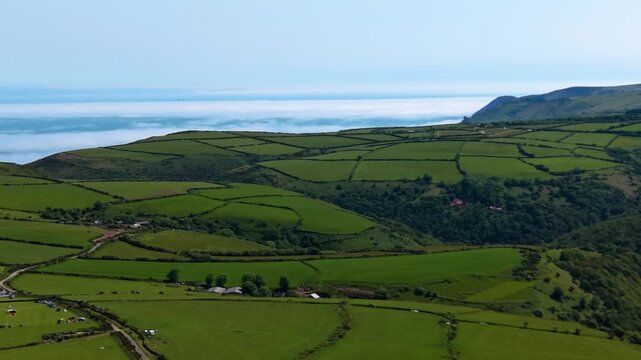 Wide Landscape Aerial of North Devon Coastal Fields with Cloud Inversion Over Ocean in Background. Spectacular Footage of Natural Phenomenon. 4K.