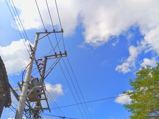 Fototapeta premium Electrical utility pole with transformer and power lines under bright blue sky infrastructure