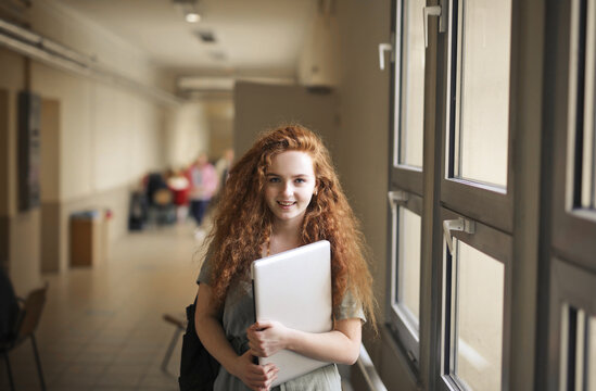Smiling teenage student with red hair in a school hallway