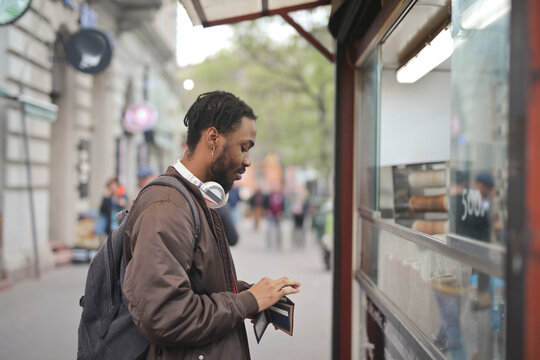 Young black man buying street food at a city kiosk