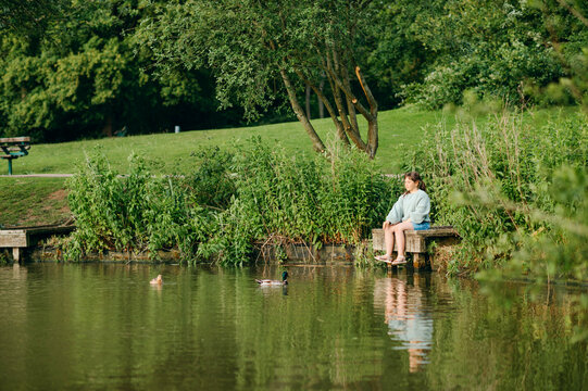 Young girl sitting on a wooden dock beside a peaceful lake