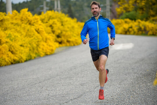 Man runs on a country road past yellow wildflowers