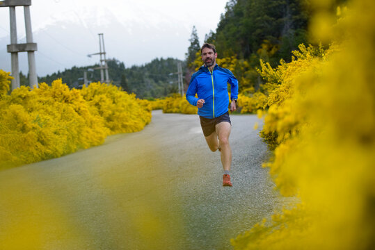 Man running on a rural road surrounded by yellow flowers