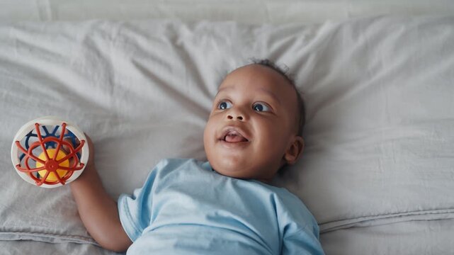 Carefree little child smiling when lying in bed, looking at mom and playing. Portrait of cute african american baby, charming toothless smile of infant boy or girl enjoying life and exploring world