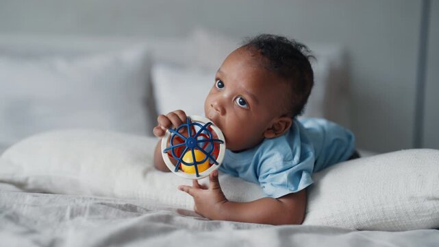 Funny black child exploring world and playing with toy in bedroom, childhood. Safety educational toys for children, development and parenting, african american infant boy or girl, teething period
