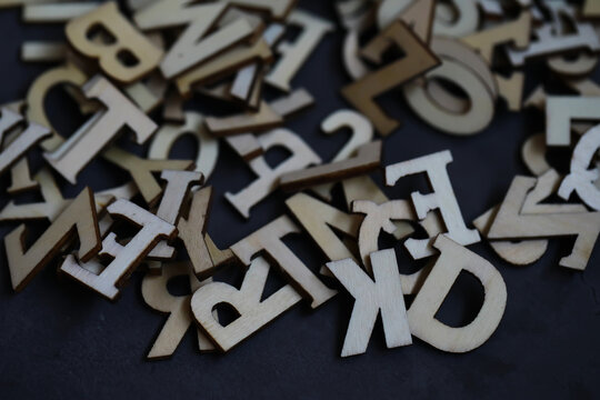 Wooden Alphabet Letters Scattered on Dark Surface for Creative Projects