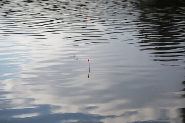 Serene Fishing Float in Tranquil Water Reflection at Sunset © alexkich