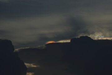 Obraz premium Dark rain clouds at dusk with a subtle iridescent cloud formation along the cloud edges. The soft rainbow colors are created by sunlight diffraction, producing a dramatic and peaceful atmospheric