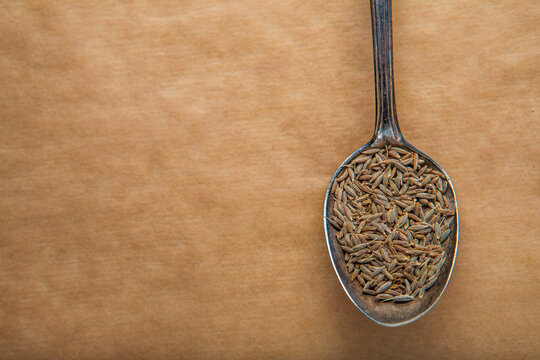 Macro shot of aromatic cumin seeds in silver spoon