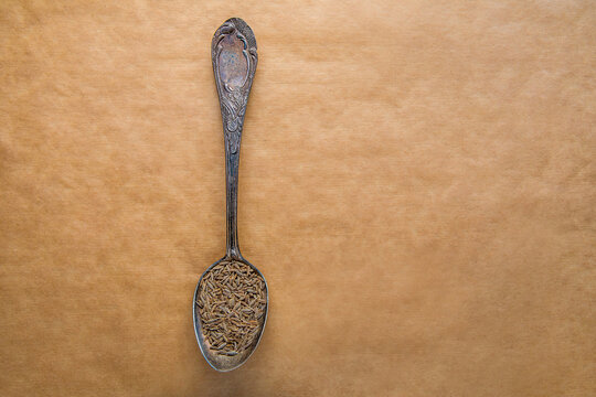 Cumin seeds in vintage silver spoon on craft background