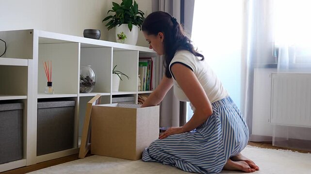 Young woman closing and putting away storage box after organizing belongings in modern home interior. Home organization and decluttering routine concept