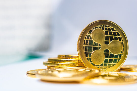  Moneda f&iacute;sica Gold Ripple XRP colocada sobre una pila de monedas con un fondo c&aacute;lido de luz amarilla dorada, imagen editorial c&aacute;lida de la moneda Ripple XRP para noticias de corridas alcistas de XRP,