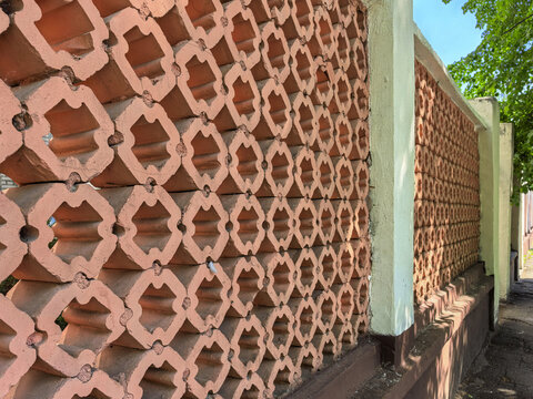 Decorative red brick fence with geometric pattern and concrete pillars