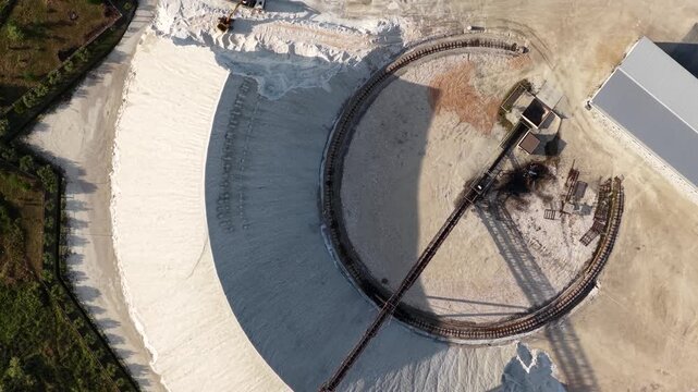 Aerial view of the circular conveyor belt and large white salt mounds at the Narta Lagoon industrial facility in Vlore, Vlore County, Albania.