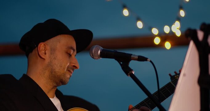 Male Acoustic Guitarist Singing on Outdoor Dusk Stage