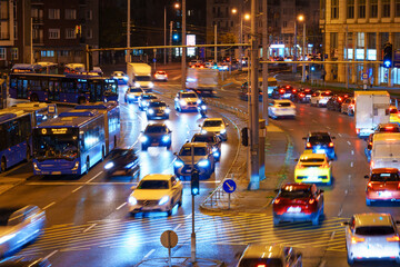 Obraz premium Urban night traffic flow in Budapest featuring cars, buses, and illuminated city streets with motion blur effect.