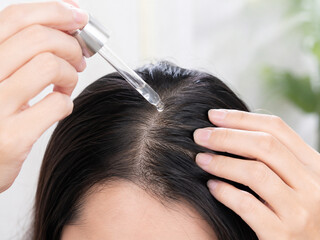 Naklejka premium Woman Applying Scalp Treatment Serum with Dropper for Hair Care