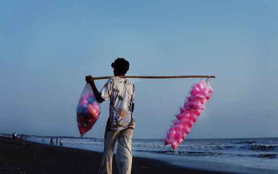 Mumbai, India &ndash; 10 June 2026: Street vendor carrying colorful cotton candy while walking along a beach area.
