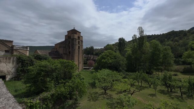 Ancient Stone Church Over Rural Orchard Under Cloudy Hills