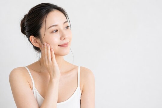 スキンケア女性が頬をなでる明るい横顔