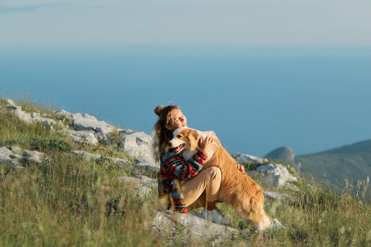 A woman hugs her Border Collie in mountain scenery with soft natural light. Emotional atmosphere creates peaceful adventure feeling.