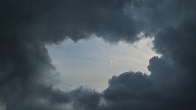 Dark clouds fill the sky as a break forms, showing patches of blue. This transition highlights the unpredictable nature of weather and atmospheric changes