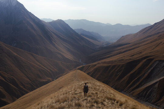 Backpacker trekking in Caucasus mountains with a stunning panoramic view of Khada gorge, Georgia country