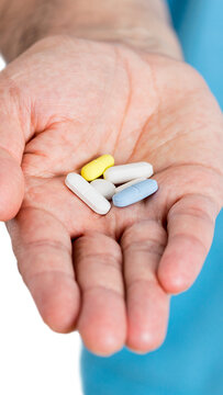 man's hand holding out some white pills ove