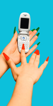 Hands dialing silver flip phone with red and green nails on blue background. Concept of retro mobile communication, Y2K nostalgia, phone contact and tech history.