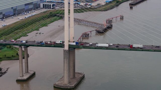 Aerial view of Queen Elizabeth II Bridge with heavy traffic crossing the River Thames near industrial docks Dartford, England, United Kingdom.