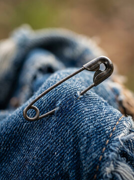 Classic safety pin attached to classic blue denim jeans fabric