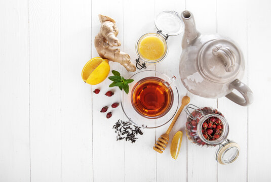 Cup tea with honey lemon and Rose Hip on white wooden board top view. Medicinal drink with mint and ginger.