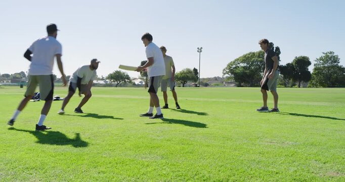 Running diverse male friends chasing yellow flying disc on grassy sports field, sports bags